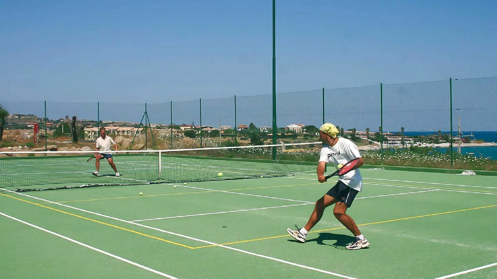 Campo da tennis con giocatori e vista sul mare e sulla costa