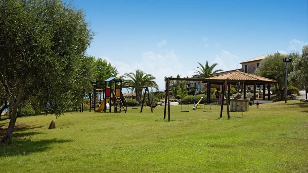 Area giochi per bambini con scivoli e altalene nel prato verde