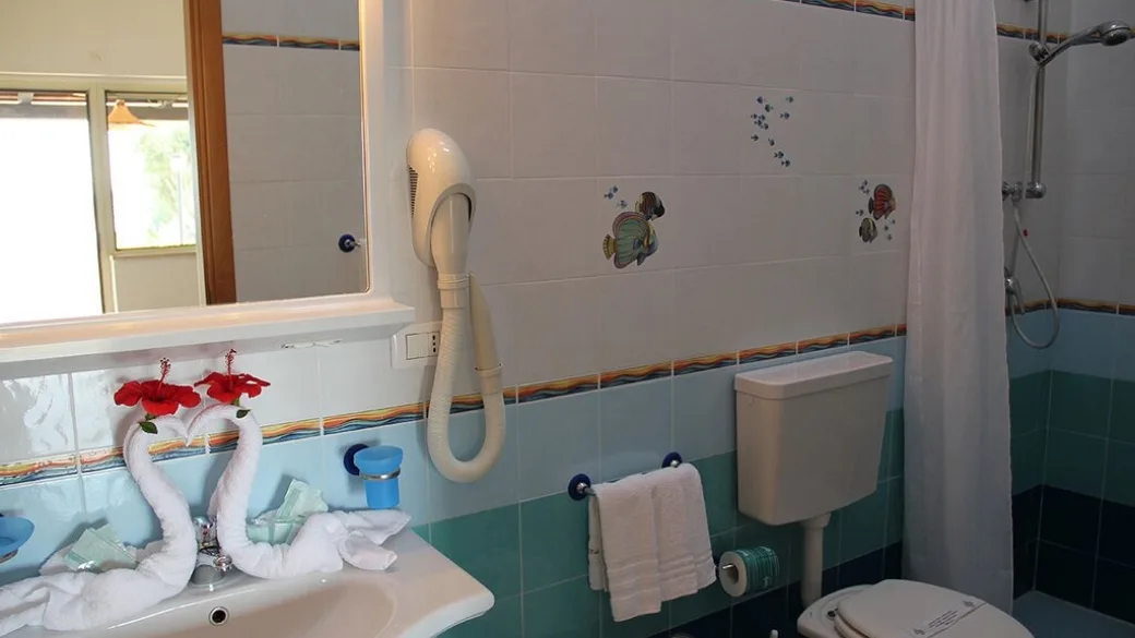 Bagno con doccia, lavabo e piastrelle decorate a tema marino