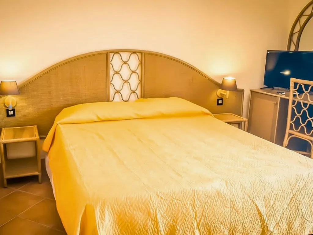 Camera con letto matrimoniale, copriletto giallo e televisore