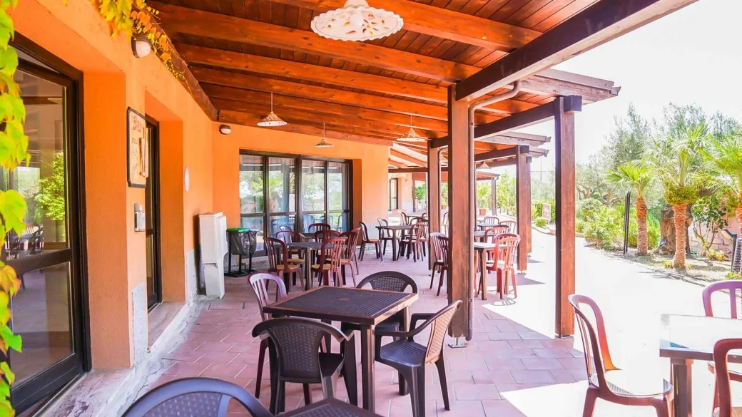 Terrazza esterna coperta con tavoli e sedie e tettoia in legno