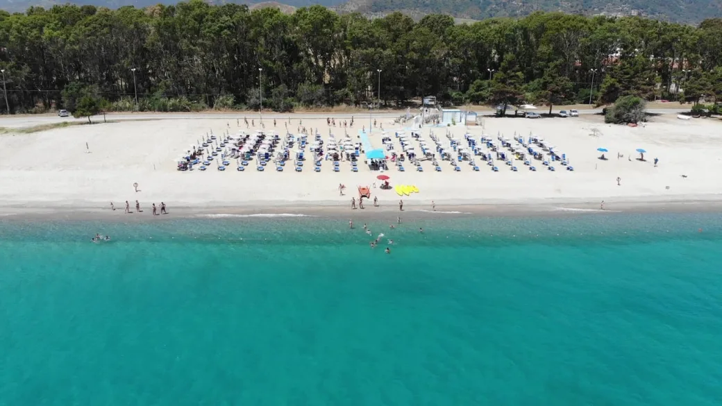 Veduta aerea della spiaggia sabbiosa con ombrelloni e mare turchese