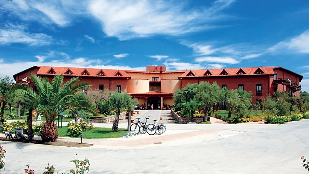 Facciata dell'hotel in mattoni rossi con biciclette all'ingresso e cielo azzurro