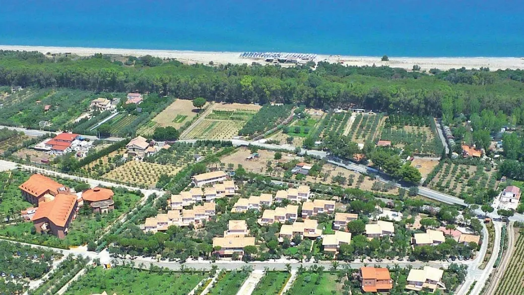 Veduta aerea del resort immerso nel verde con spiaggia e mare sullo sfondo