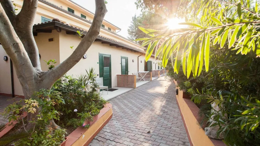 Vialetto in pietra tra la vegetazione con camere dell'hotel