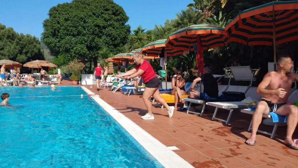 Attività di animazione a bordo piscina con ospiti e ombrelloni colorati