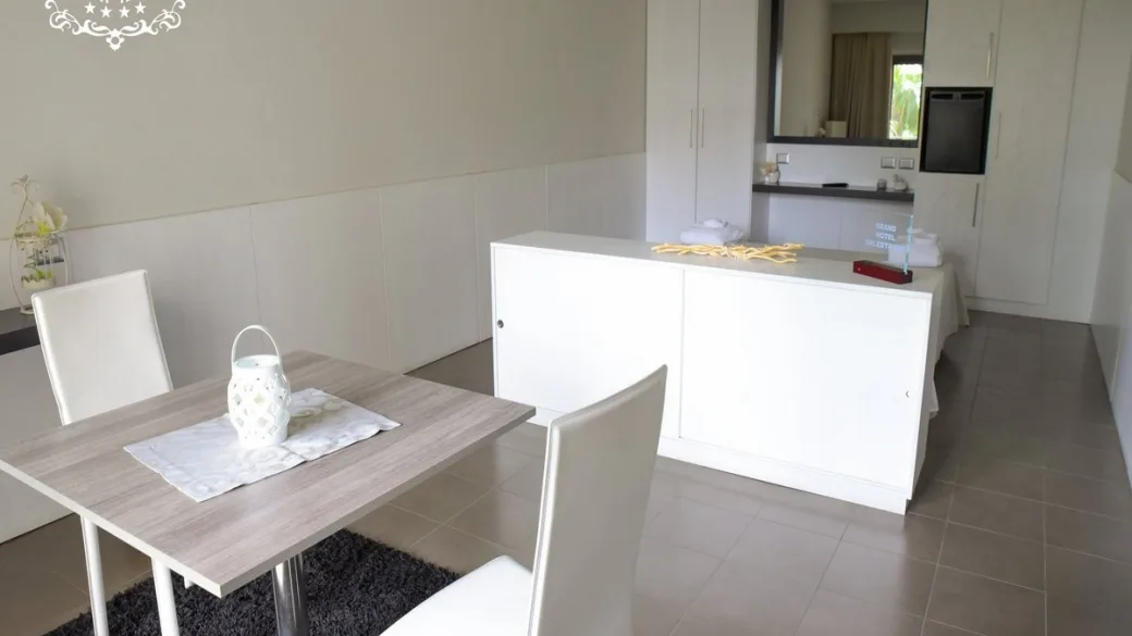 Zona soggiorno della suite con tavolo da pranzo e mobile bianco