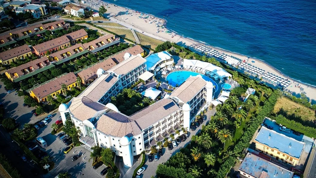 Veduta aerea dell'hotel a ferro di cavallo con piscina e accesso alla spiaggia