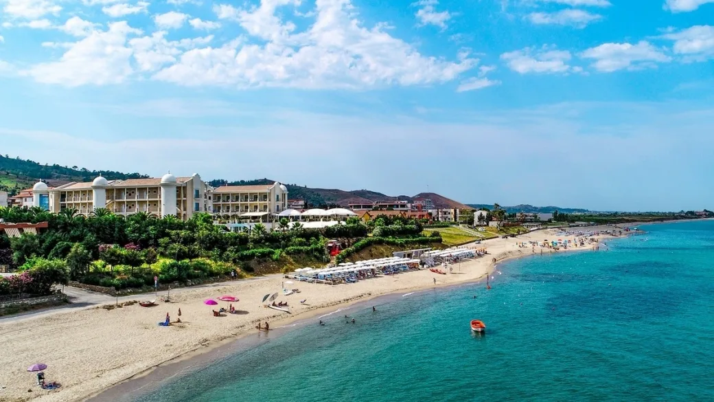 Vista aerea della spiaggia sabbiosa con hotel immerso nel verde