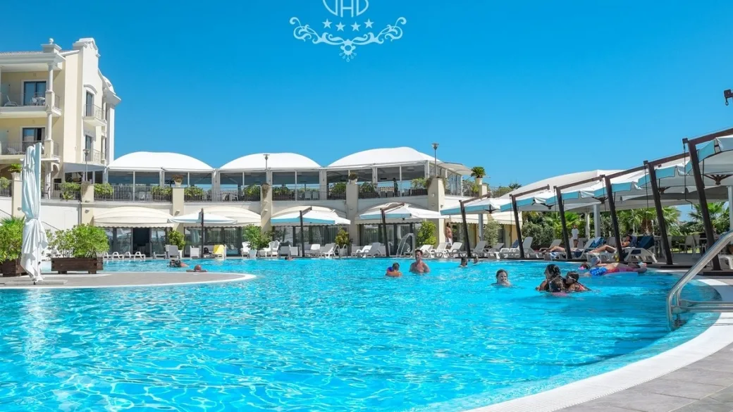 Piscina del resort con ombrelloni, gazebo e ospiti in acqua