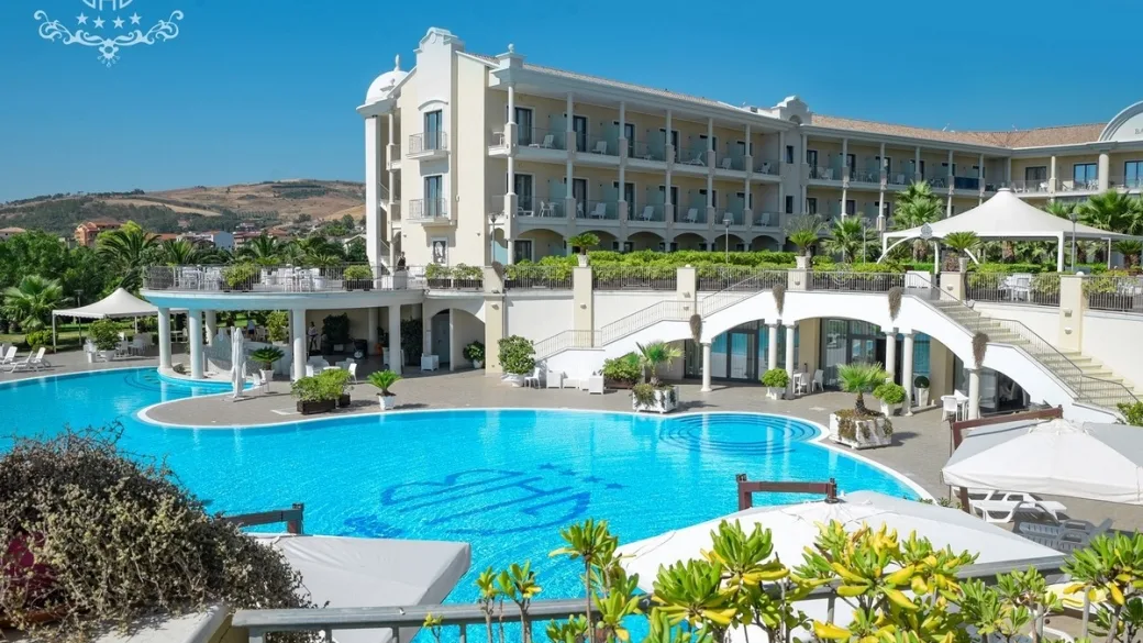 Esterno dell'hotel con grande piscina, terrazza e scalinata elegante