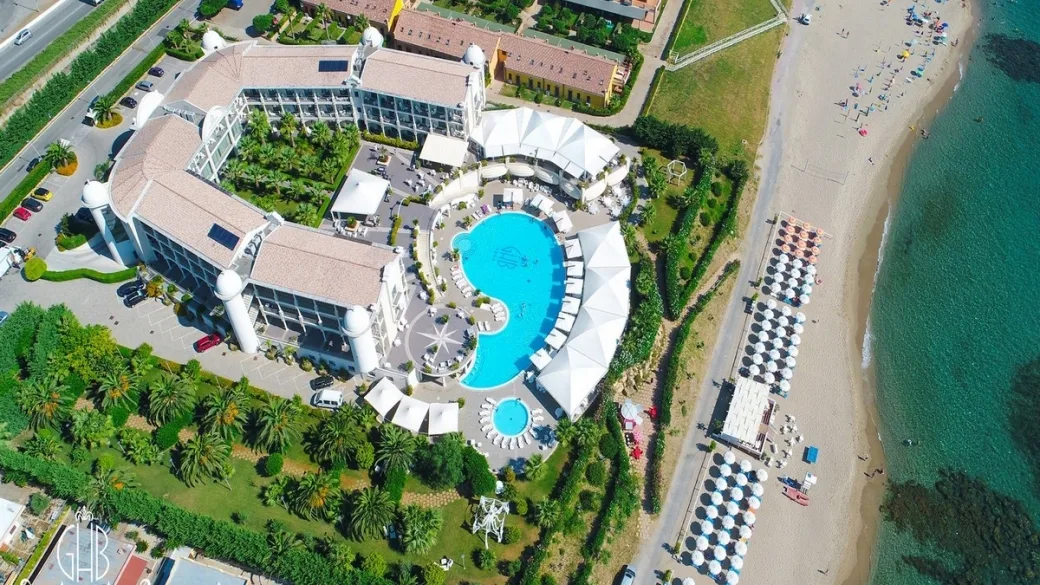Vista aerea del resort a forma curva con piscina e spiaggia attrezzata