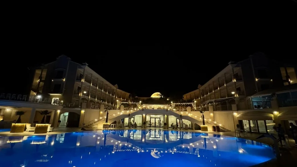 Hotel illuminato di notte con piscina riflettente e luci scenografiche