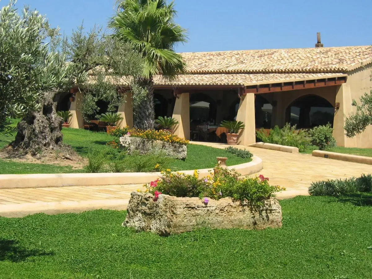 Edificio rustico con portico ad archi, giardino fiorito e vialetto pavimentato