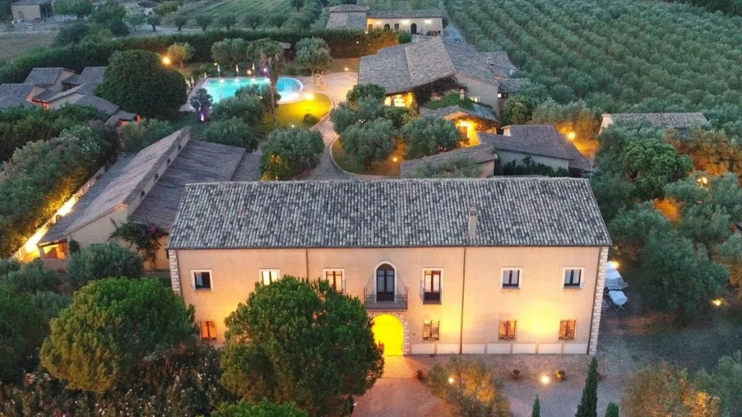 Vista aerea del complesso al tramonto con edificio illuminato e piscina
