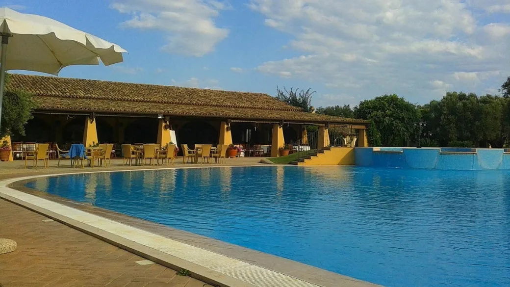 Piscina con ristorante coperto sullo sfondo e cielo nuvoloso