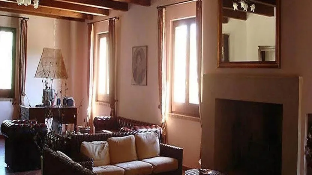 Soggiorno rustico con divani in pelle, camino e travi a vista