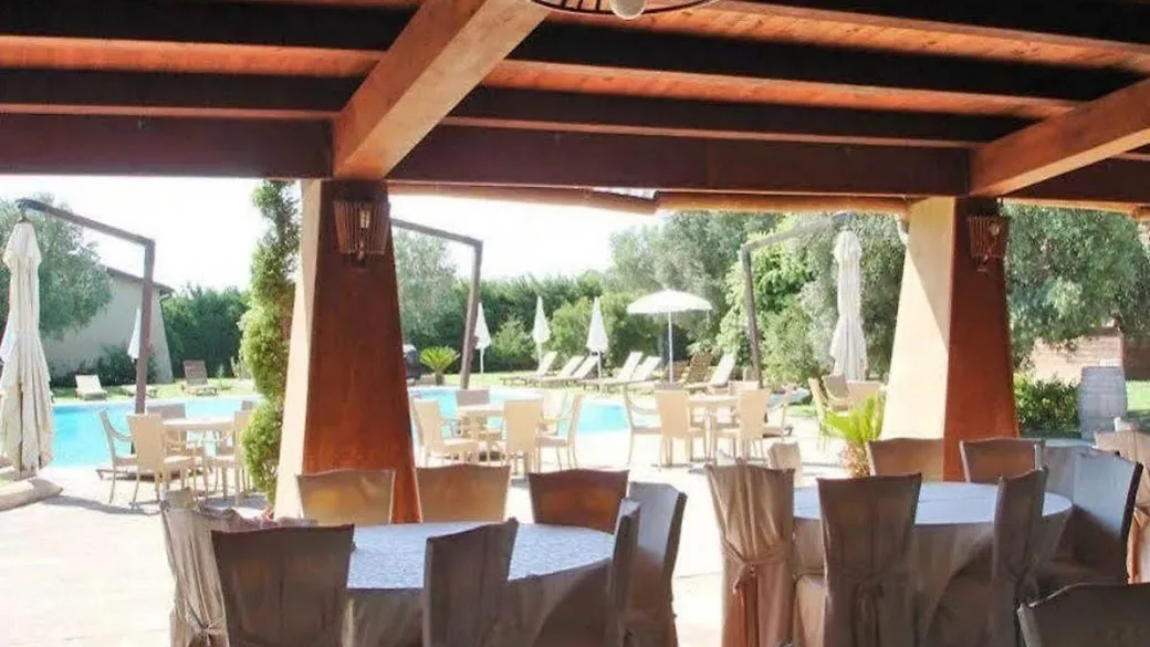 Area ristorante all'aperto con pergolato in legno e vista sulla piscina