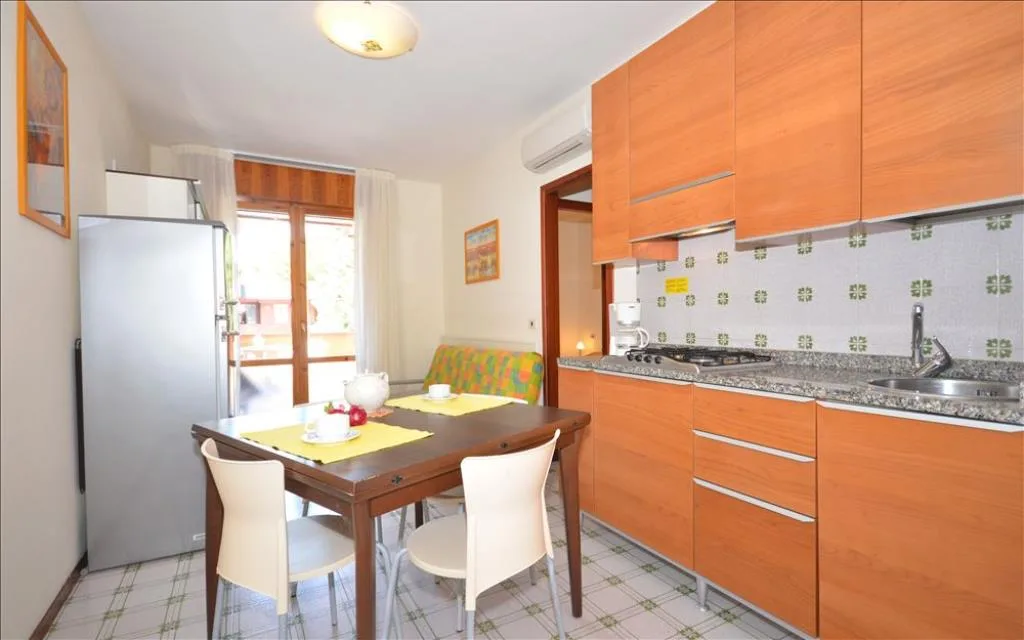 Cucina con mobili in legno, frigorifero e tavolo da pranzo apparecchiato