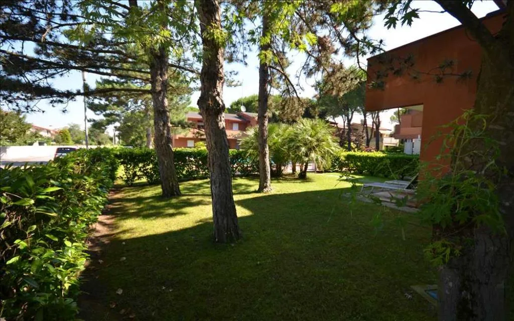 Giardino ombreggiato con alberi di pino e prato verde nel residence