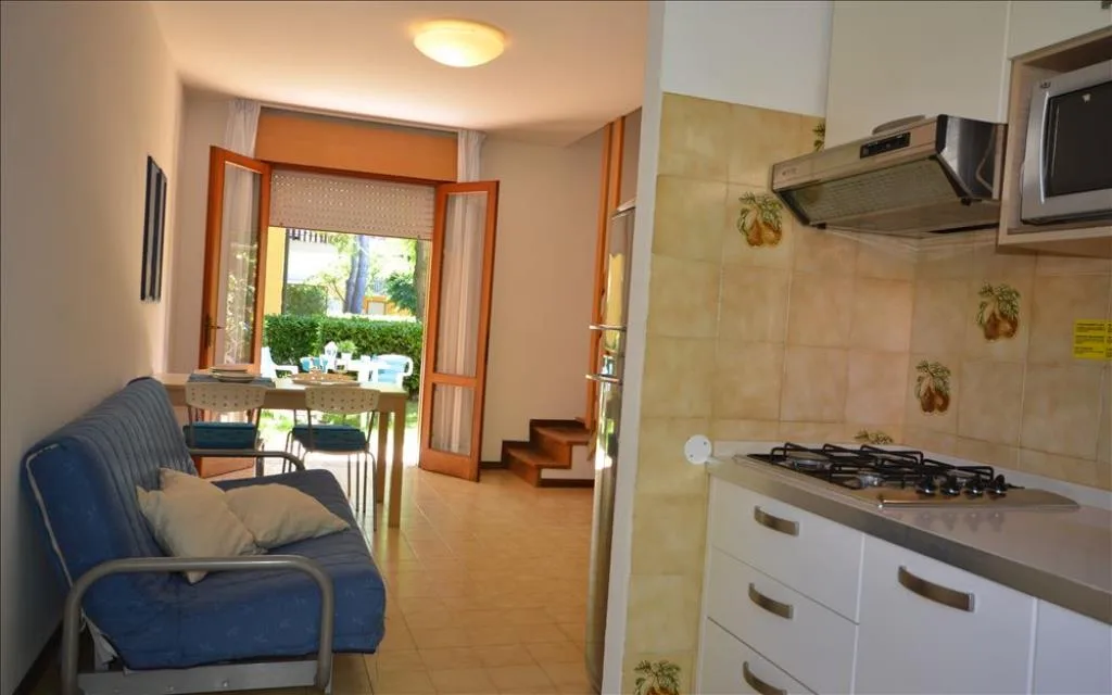 Angolo cottura bianco con divano e uscita sul giardino