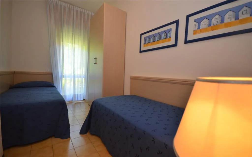 Camera doppia con letti blu, armadio e lampada da comodino