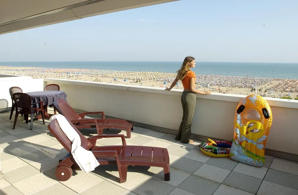Terrazza con lettini e vista panoramica sulla spiaggia affollata e sul mare