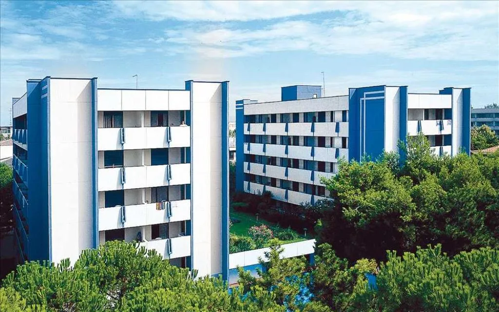Esterno della residenza con edifici bianchi e blu tra i pini