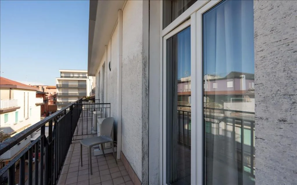 Balcone con sedia e vista sui palazzi circostanti sotto un cielo sereno