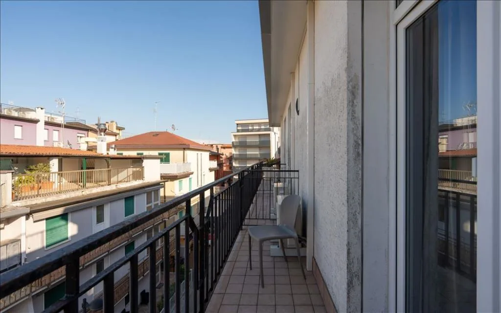 Balcone lungo con sedia grigia e vista panoramica sulle case del quartiere