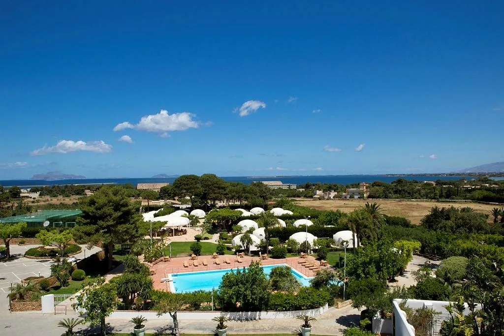 Vista panoramica del resort con piscina, bungalow bianchi e mare all'orizzonte