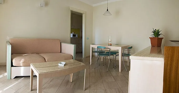 Soggiorno dell'appartamento con divano, zona pranzo e accesso alla cucina
