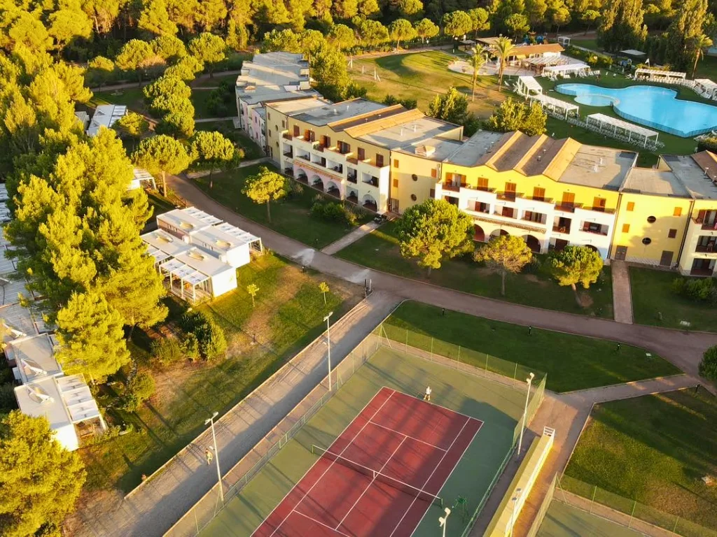 Veduta aerea del resort immerso nella pineta con campo da tennis