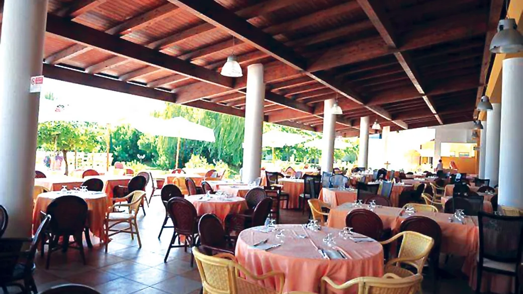 Ristorante coperto all'aperto con tavoli rotondi e vista sul giardino