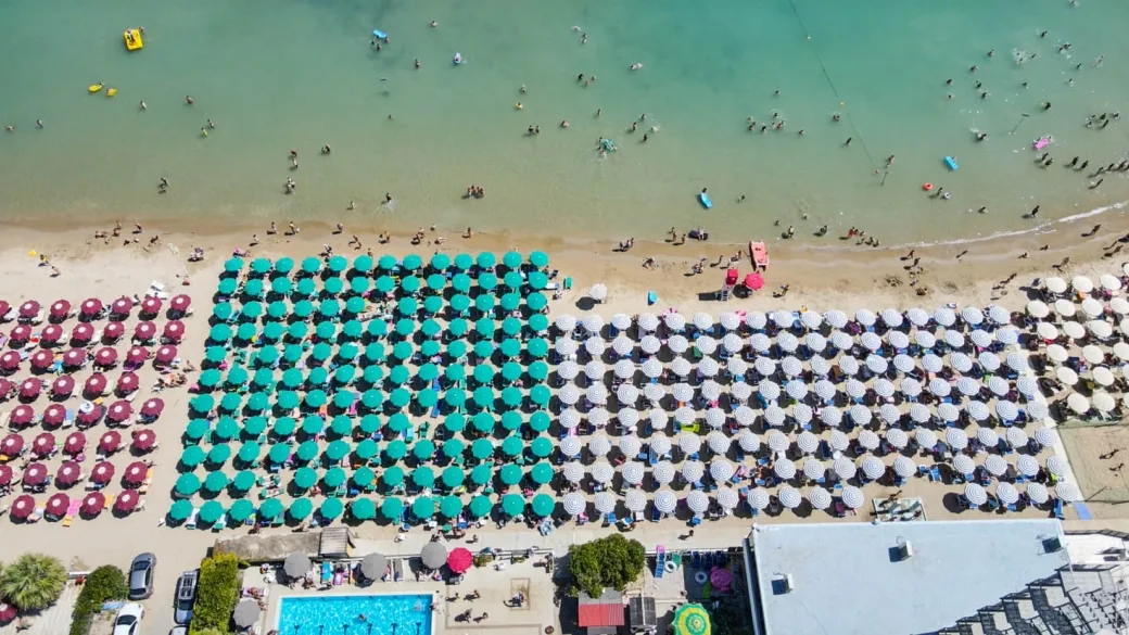Veduta aerea della spiaggia con ordinate file di ombrelloni colorati e mare cristallino