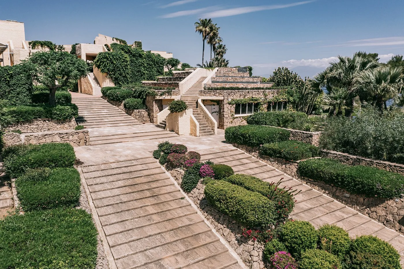 Giardini terrazzati con scalinate in pietra e siepi curate