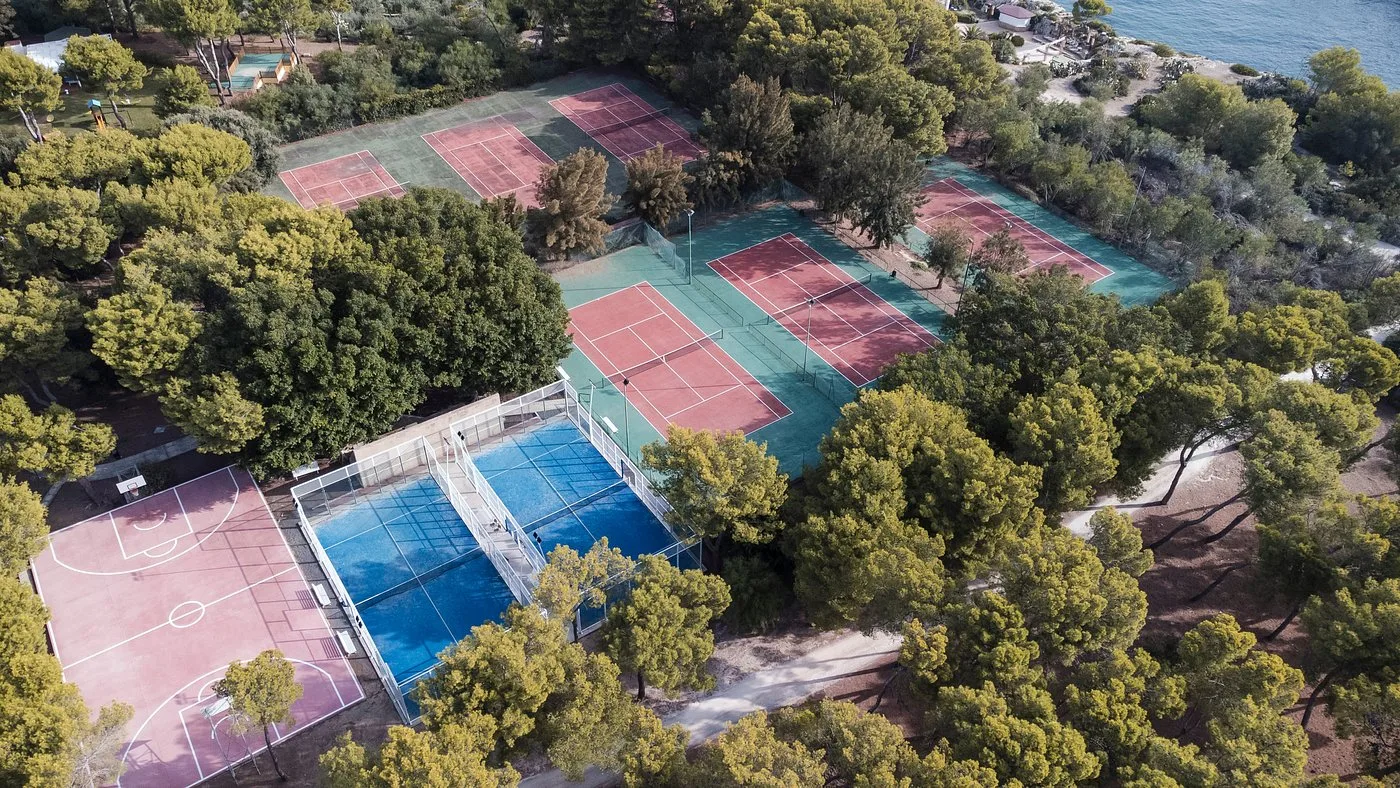 Vista aerea dei campi sportivi da tennis, padel e basket tra i pini