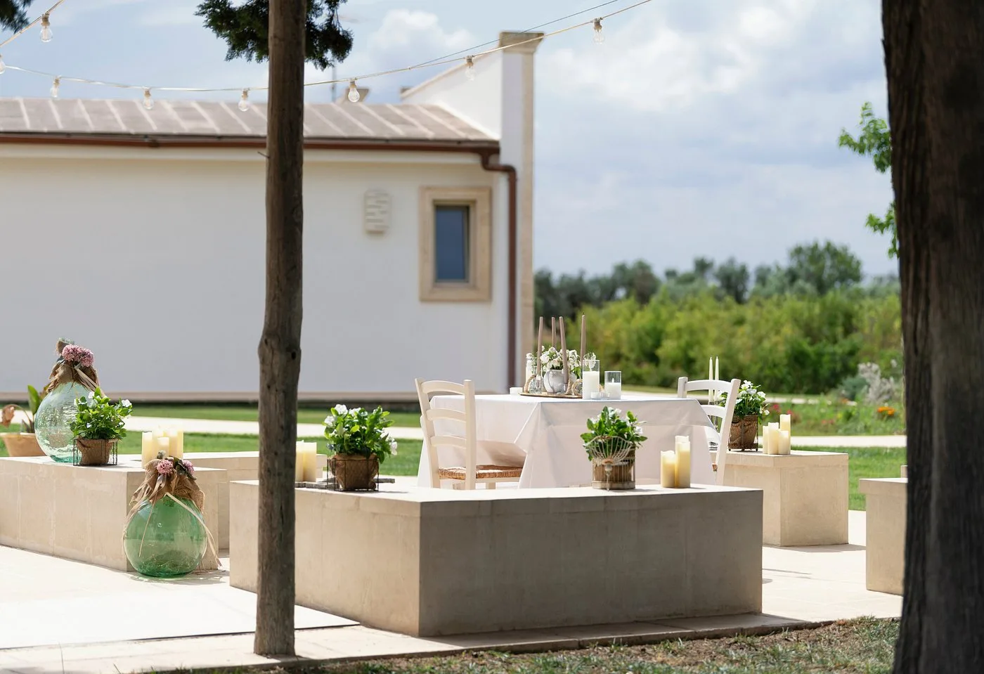 Tavolo allestito all'aperto con decorazioni, candele e luci festive nel giardino