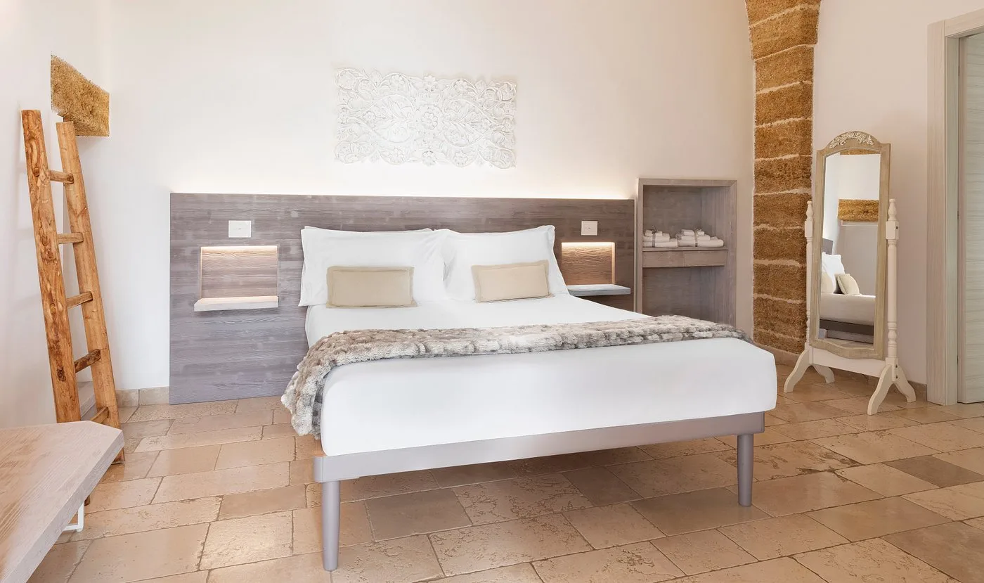 Camera luminosa con letto king size, decoro a parete e colonna in pietra