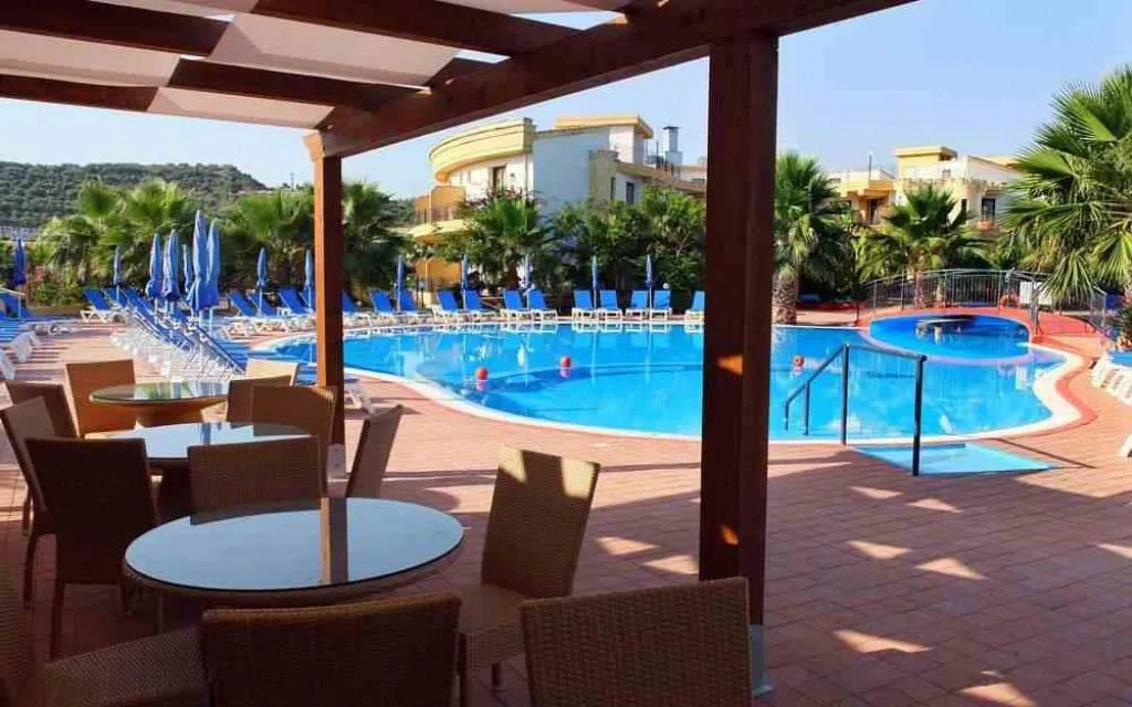 Area relax con pergolato in legno, tavoli e sedie affacciata sulla piscina