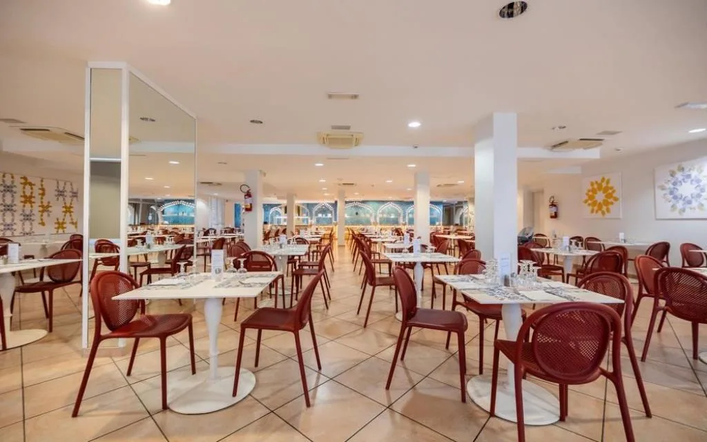 Sala ristorante interna con tavoli apparecchiati e sedie rosse