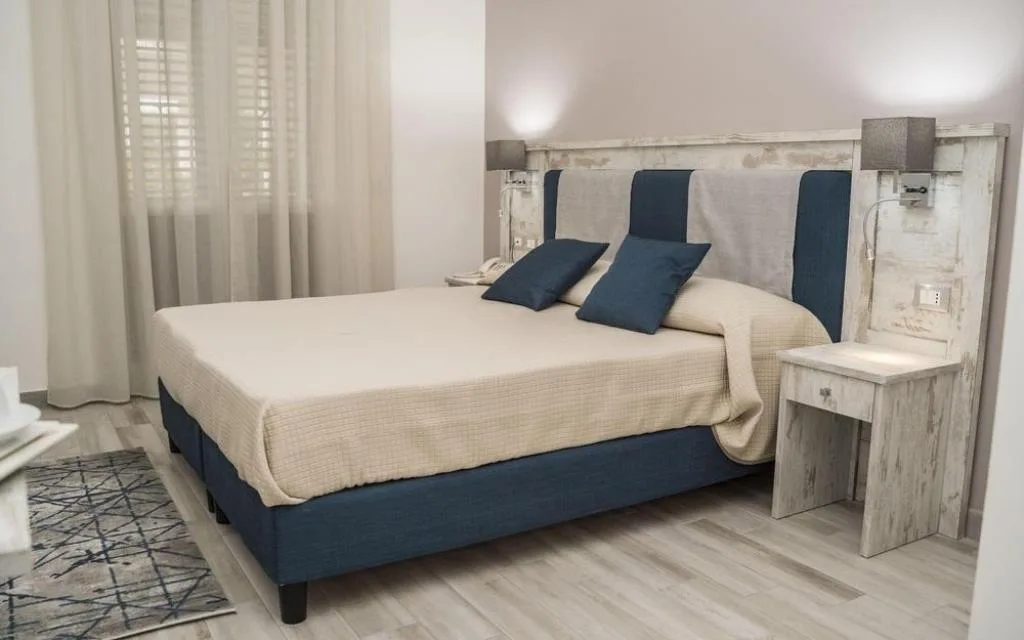 Camera matrimoniale elegante con testiera blu e beige e comodini in legno decapato