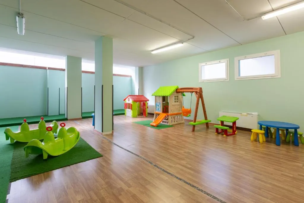 Sala giochi per bambini con scivoli, casette e giochi colorati