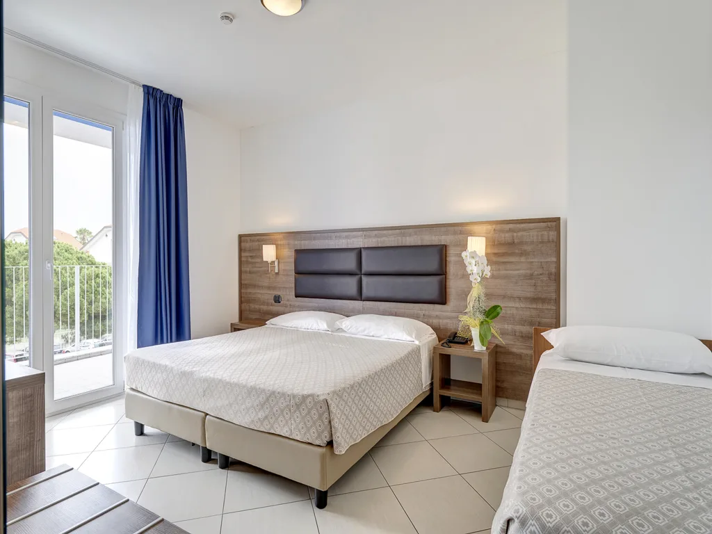 Camera tripla con letto matrimoniale e singolo, balcone e parquet chiaro
