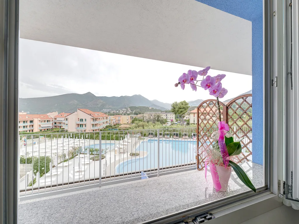 Vista dalla finestra del balcone con orchidea sulla piscina e montagne