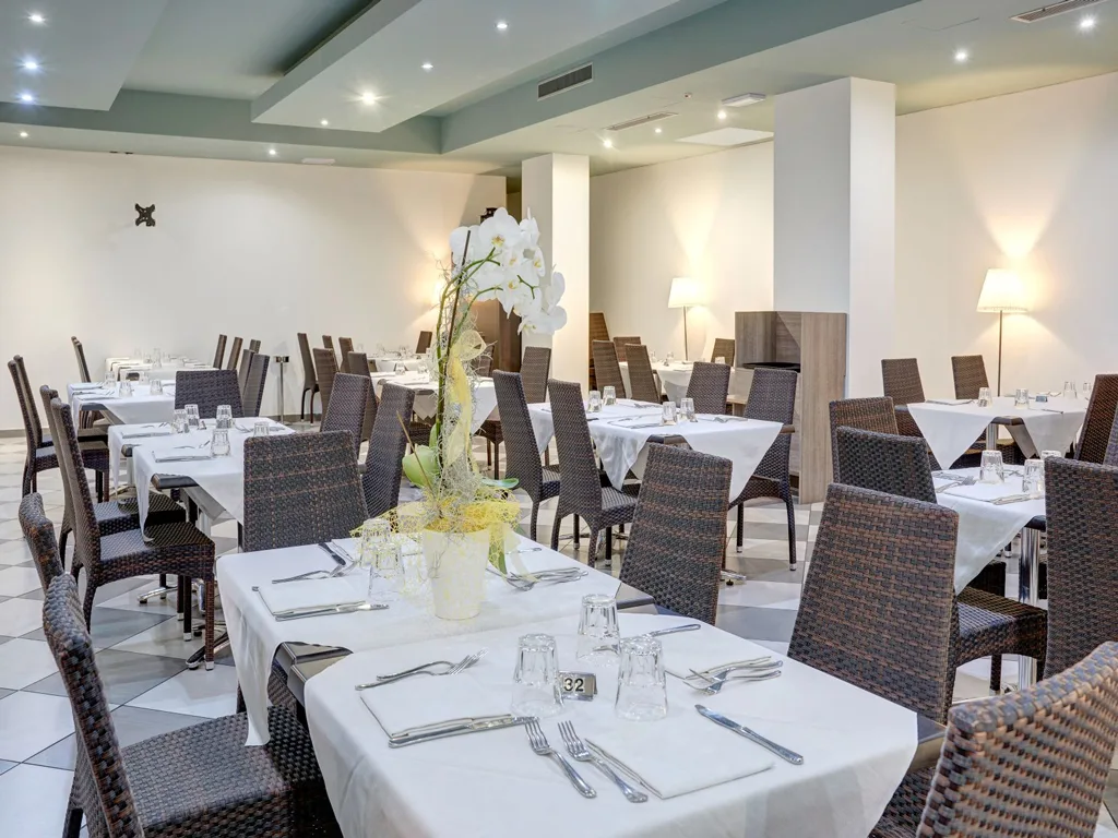 Sala ristorante elegante con tavoli apparecchiati e decorazioni floreali