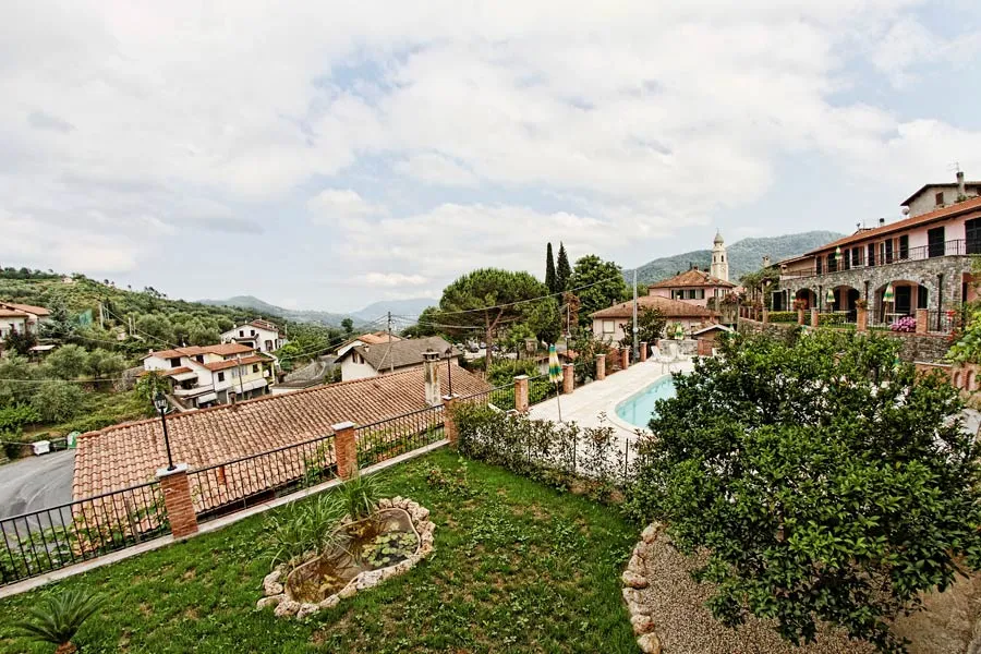 Vista panoramica sul borgo collinare con piscina, giardino e campanile