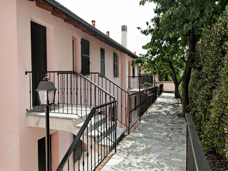Esterno di edificio rosa con scale in pietra, ringhiere in ferro e vialetto lastricato