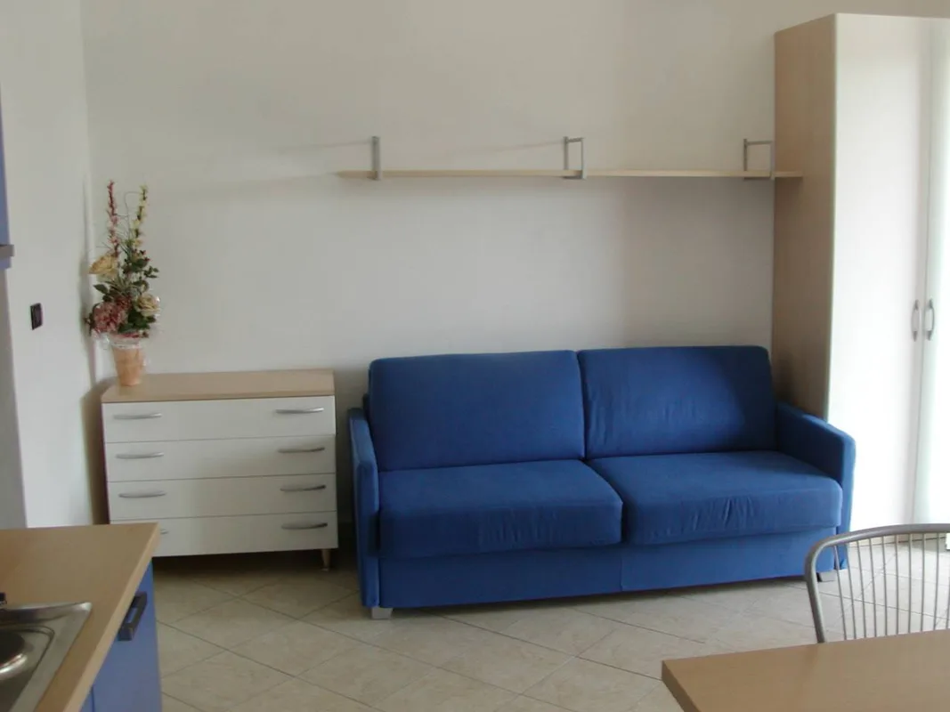 Soggiorno con divano blu, cassettiera bianca e mensola a parete