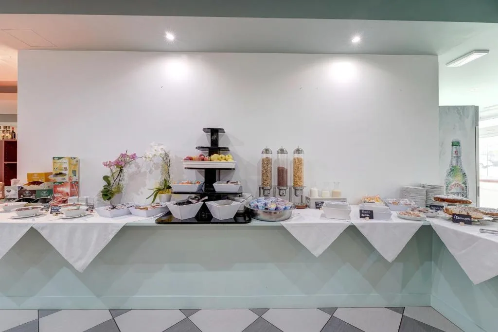 Buffet della colazione con frutta, cereali, yogurt e dolci disposti su un banco